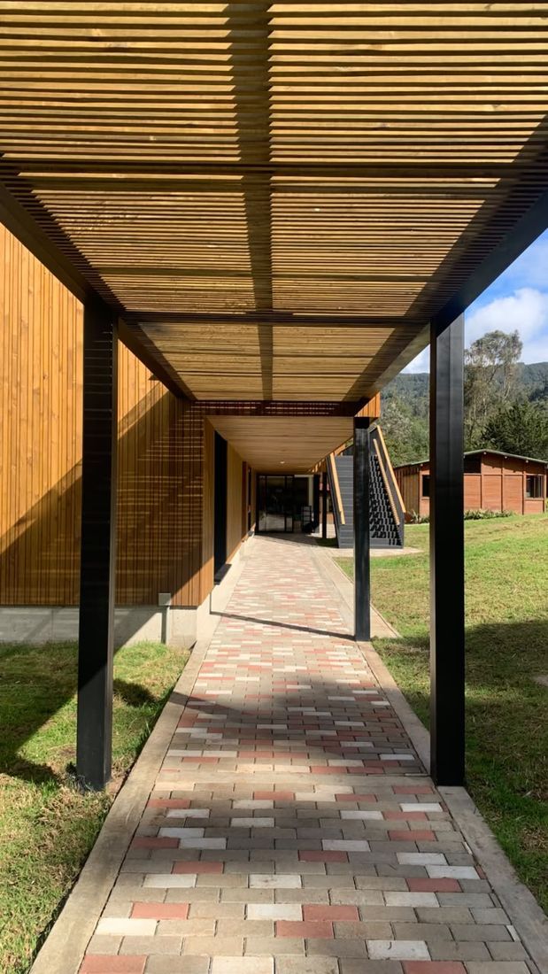 Corredor cubierto con pérgola de madera y piso en adoquín