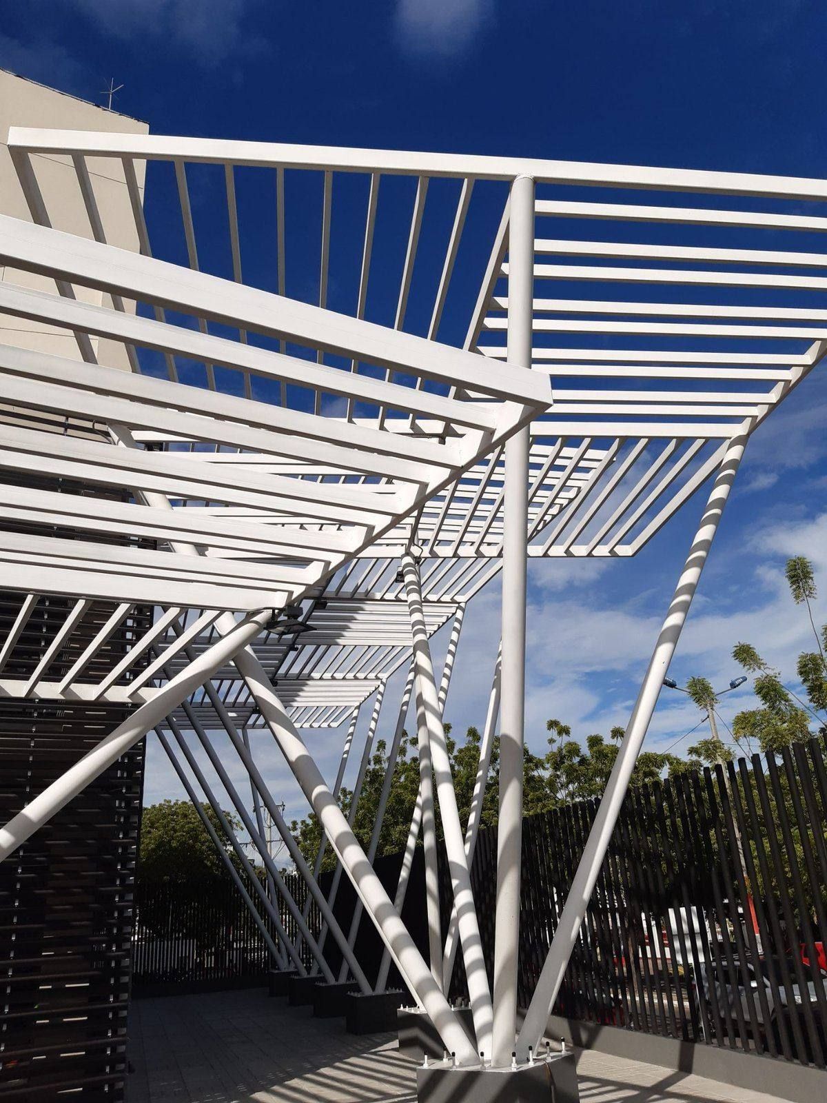 Pérgola de perfiles metálicos blancos contra el cielo